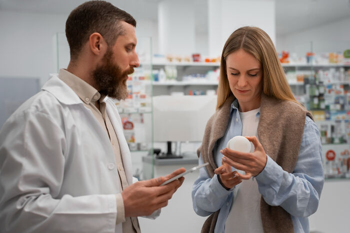 Pharmacist assisting a female patient at a drugstore, showcasing healthcare workers in action.