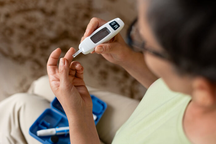A patient testing blood sugar levels with a glucose meter following advice from doctors and nurses