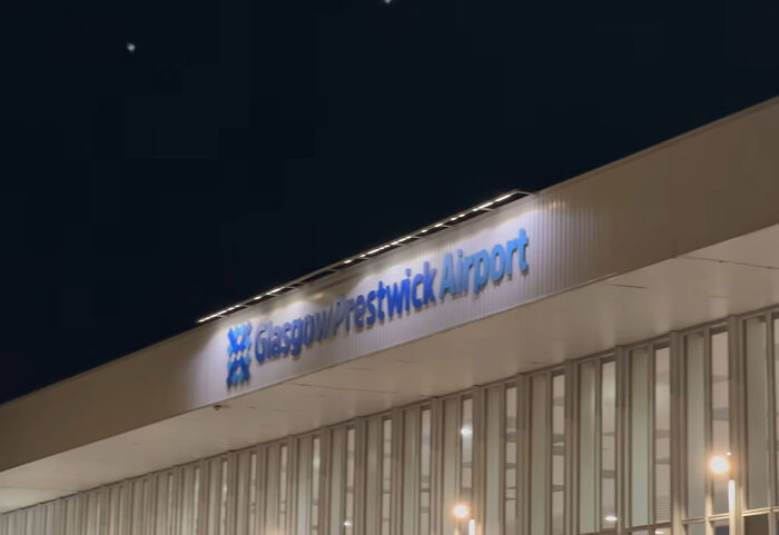 Low angle exterior view of the illuminated Glasgow Prestwick Airport terminal building at night.