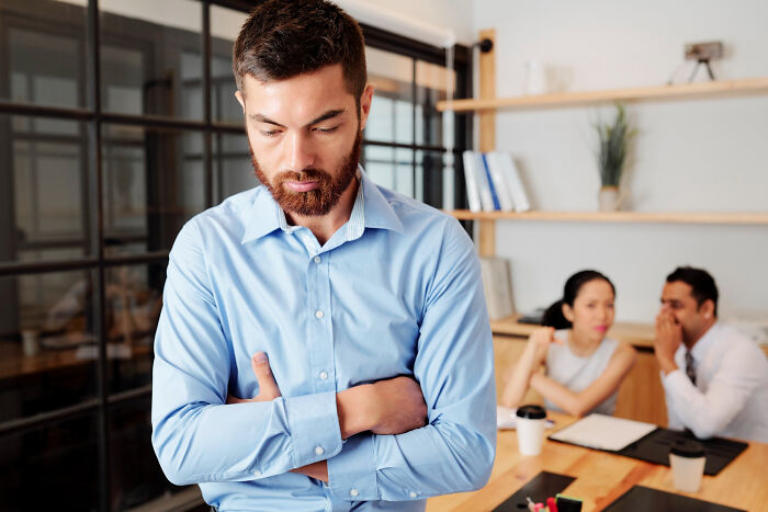 An upset office worker looking down in sadness, experiencing one of his breaking point moments.