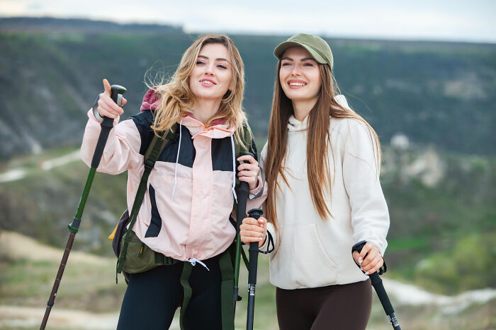 Two women hiking with trekking poles in nature