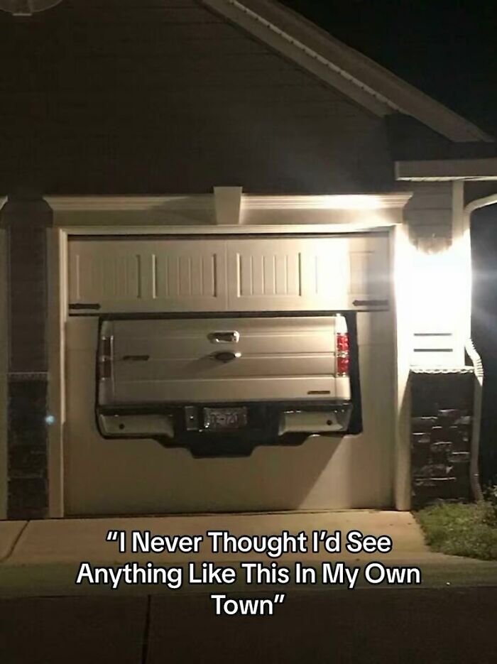 Truck bed oddly sticking through a custom cutout in a closed white garage door, showing a home renovation fiasco.