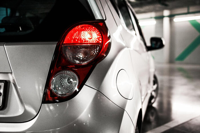 Rear brake light of a parked silver car, illustrating auto safety and emergency tips.