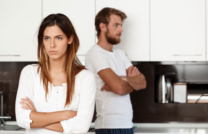 Unhappy couple standing apart in kitchen facing conflict before a marriage-ending scandal Unhappy couple standing apart in kitchen facing conflict before a marriage-ending scandal