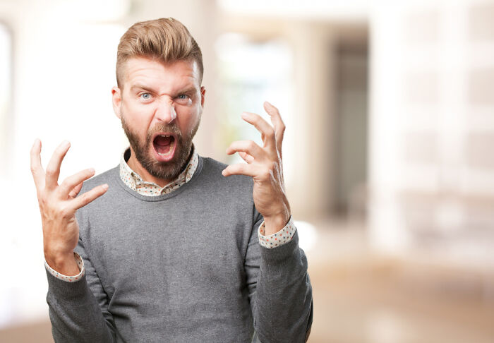 An angry man yelling with raised hands, depicting painful divorce stories.