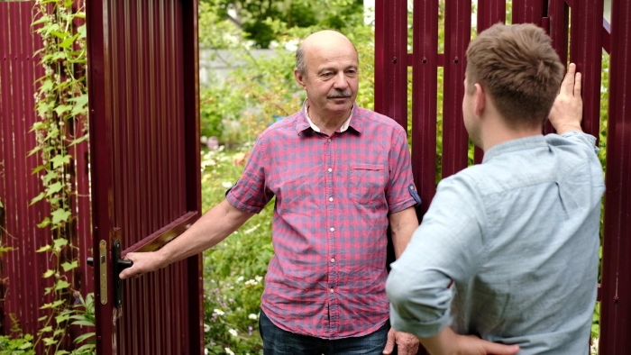 An older man talks to a younger man at a fence, illustrating an interaction with an entitled neighbor An older man talks to a younger man at a fence, illustrating an interaction with an entitled neighbor