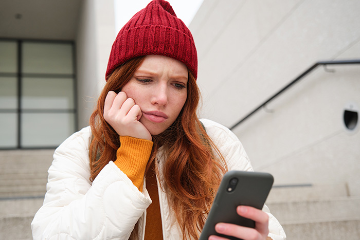 A young woman looking at her smartphone with a concerned expression, uncovering lies online. A young woman looking at her smartphone with a concerned expression, uncovering lies online.