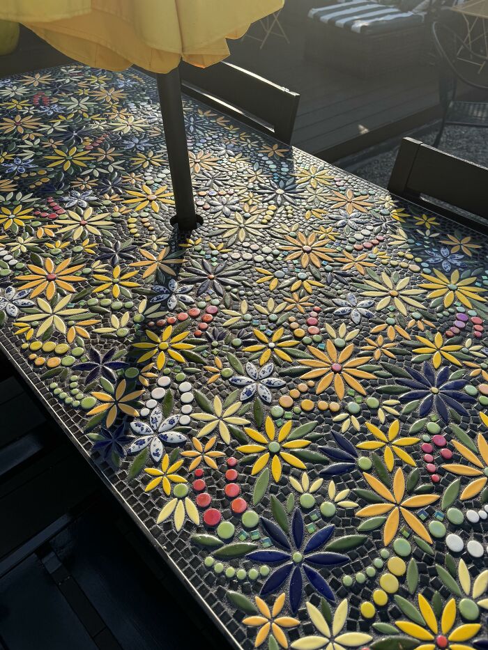 Outdoor table featuring intricate mosaic floral artwork, an example of creativity to save money on decor.