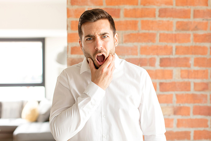 A male coworker looking shocked with mouth open as a coworker insults woman hair.
