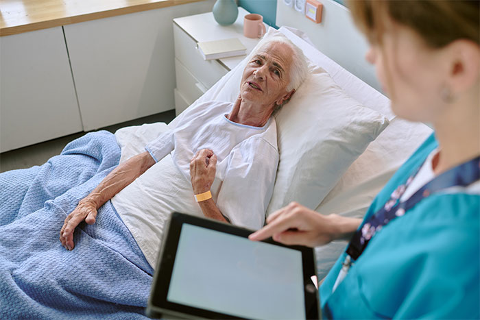 Healthcare worker having end-of-life conversations with an elderly patient in a hospital bed. Healthcare worker having end-of-life conversations with an elderly patient in a hospital bed.