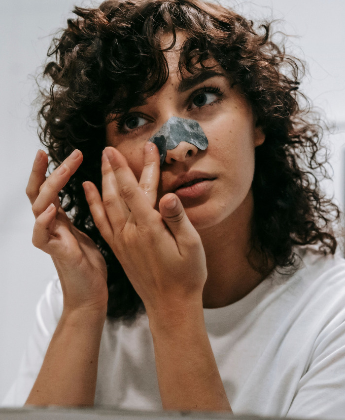 A woman applying a pore strip to treat black spots on your nose. A woman applying a pore strip to treat black spots on your nose.