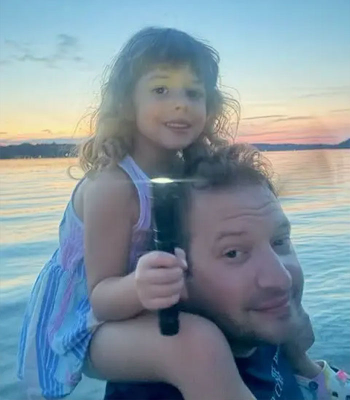 A father holding his young daughter on his shoulders near water after a custody battle A father holding his young daughter on his shoulders near water after a custody battle