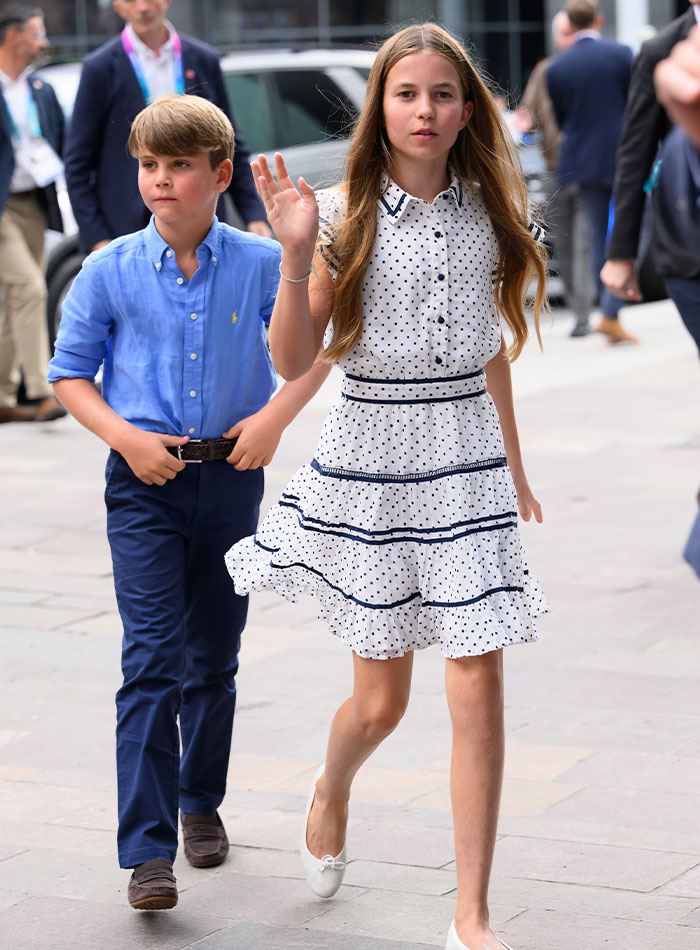 Princess Charlotte waves beside her younger brother Prince Louis as they walk outdoors. Princess Charlotte waves beside her younger brother Prince Louis as they walk outdoors.