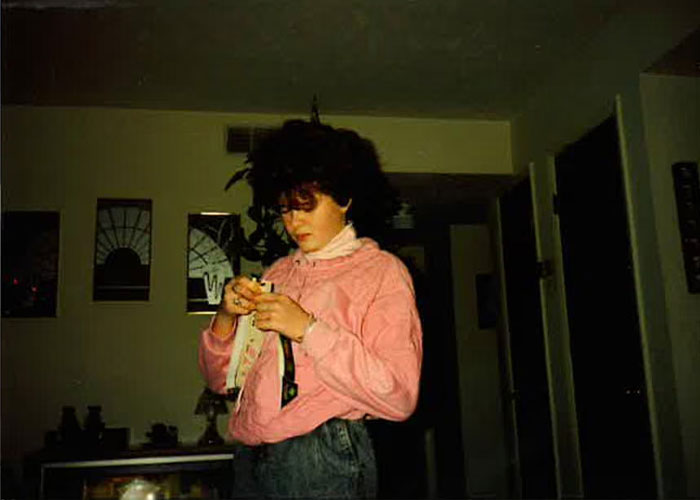 A young Christa Pike standing indoors in a pink sweatshirt.
