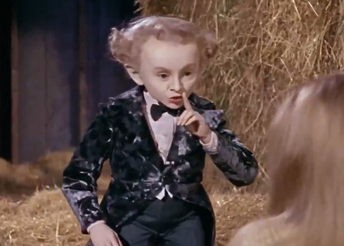 The Rumpelstiltskin Tiptoe man holding a finger to his lips, gesturing for silence in a barn. The Rumpelstiltskin Tiptoe man holding a finger to his lips, gesturing for silence in a barn.