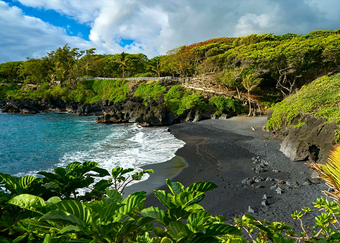 Scenic black sand beach in Hawaii where tourists often ignore beach safety warnings