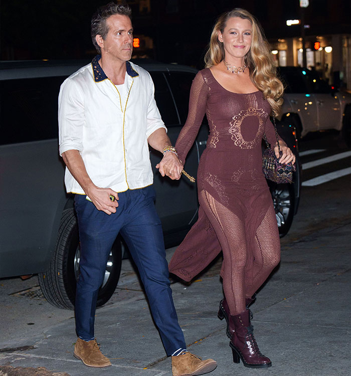 Ryan Reynolds and Blake Lively holding hands while walking outside together on a city street.