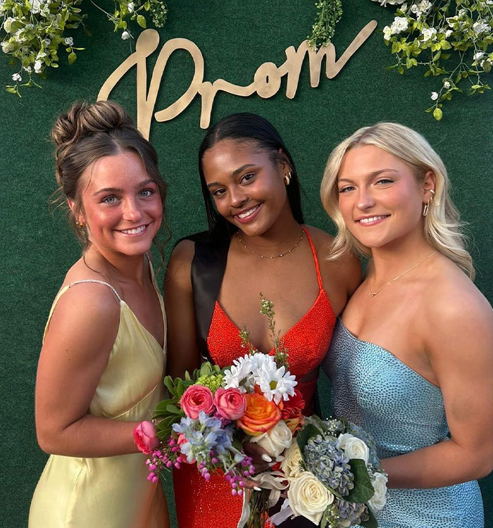Three young women in formal dresses posing at prom event Three young women in formal dresses posing at prom event