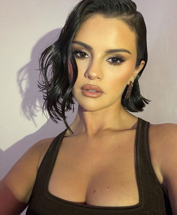 Selena Gomez posing for a close-up selfie with wavy short hair and dark eye makeup.