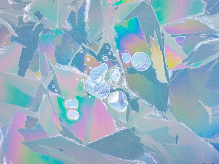 Close-up natural landscape photography showing iridescent ice patterns and trapped bubbles