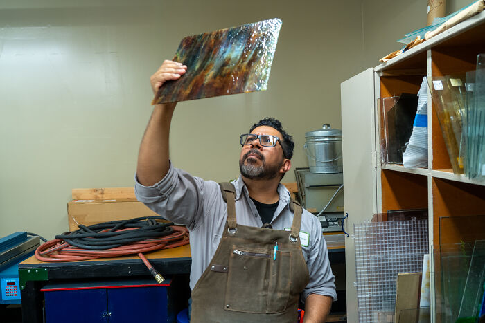 Stained-glass expert examining a textured glass sheet in workshop Stained-glass expert examining a textured glass sheet in workshop