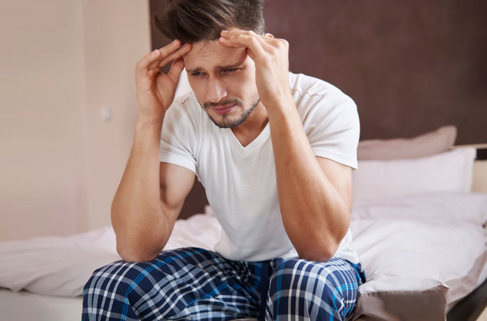 Distressed man holding his head on the bed after learning about the marriage-ending scandal. Distressed man holding his head on the bed after learning about the marriage-ending scandal.
