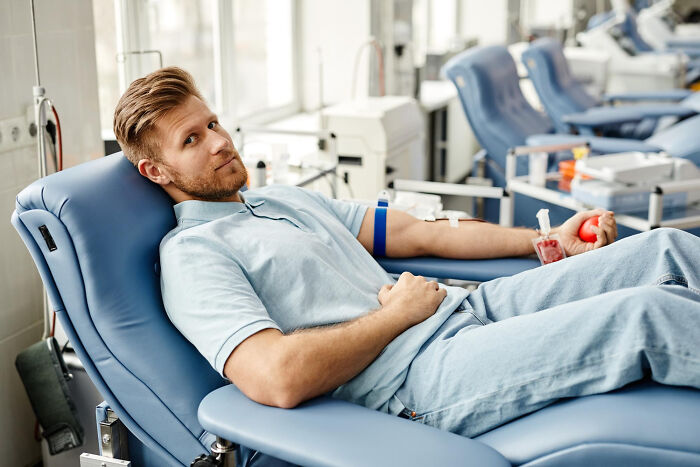 A man donating blood in a clinic, a common scenario seen by healthcare workers on shift