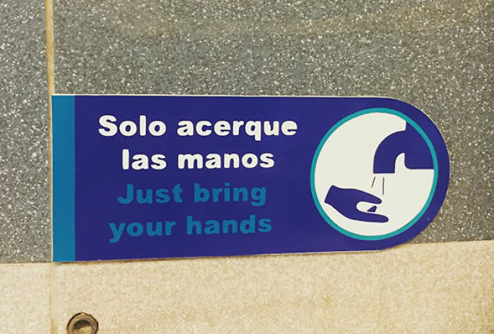 Handwashing sign with translation fails reading Just bring your hands under a faucet icon.