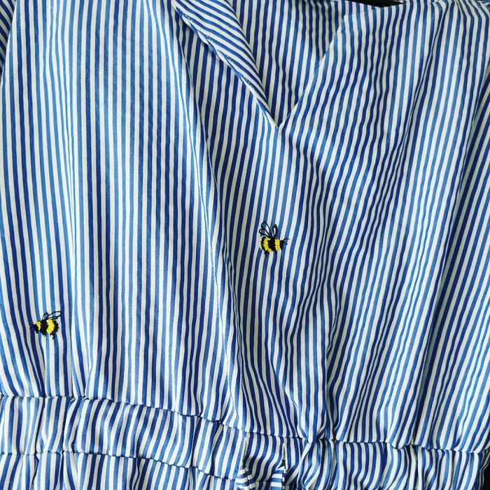 Tiny bumblebees embroidered on a blue striped top, showcasing how creativity can save money.