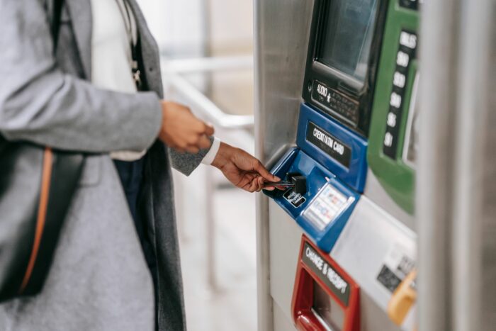 A person inserting a card into a machine to access money in bank account. A person inserting a card into a machine to access money in bank account.