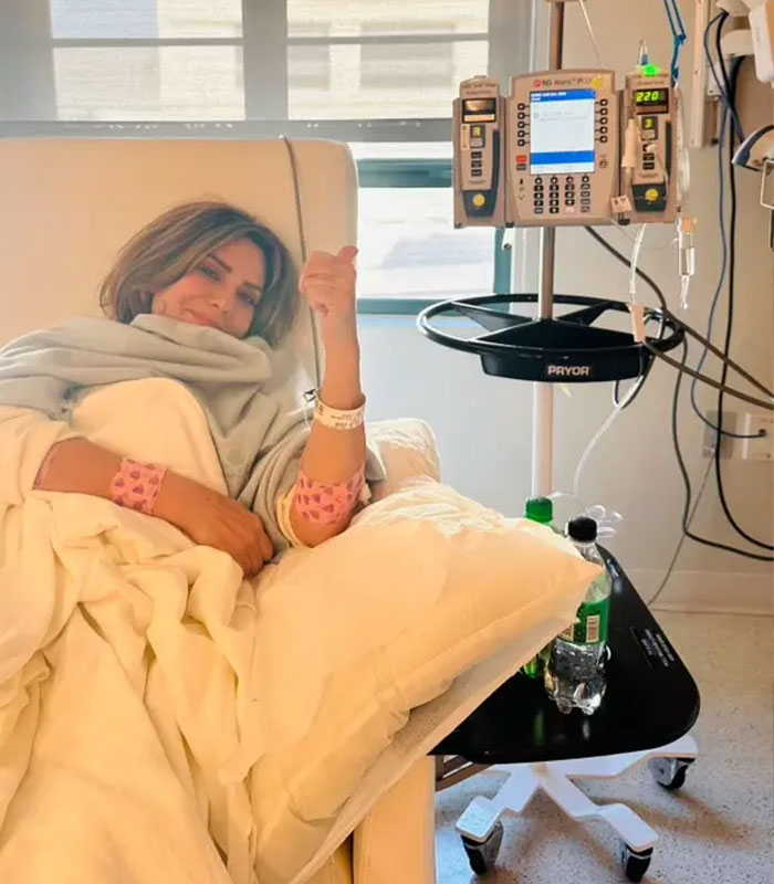 An air hostess gives a thumbs-up from a hospital bed, recovering from a health crisis.