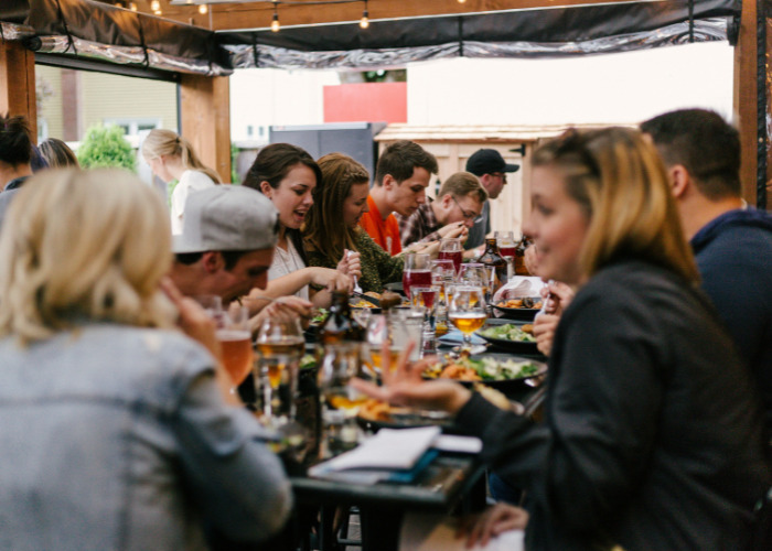 Group of friends eating together while dining out at an outdoor restaurant Group of friends eating together while dining out at an outdoor restaurant