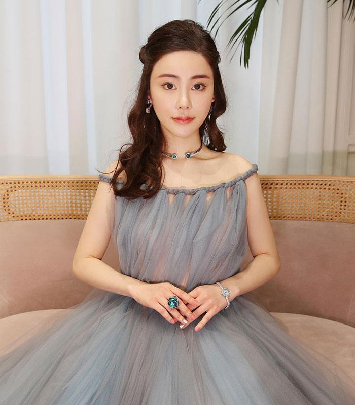 Woman in gray sheer dress sitting with jewelry accessories Woman in gray sheer dress sitting with jewelry accessories