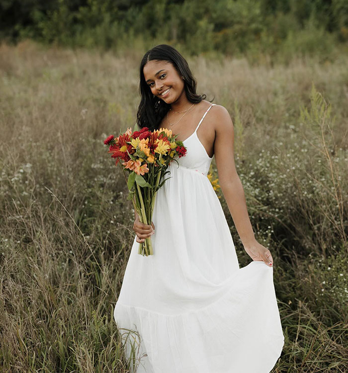 Woman in white dress holding flowers standing in field sorority scandal Woman in white dress holding flowers standing in field sorority scandal