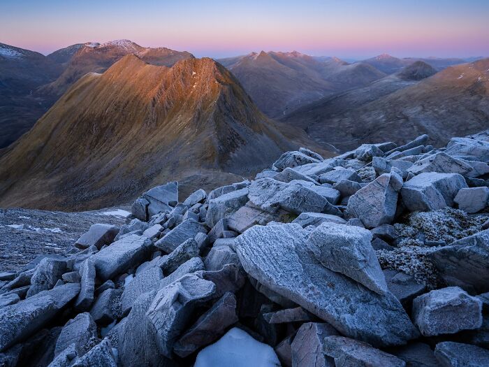 Frost covered rocks overlooking mountain ridges at twilight for Natural Landscape Photography Awards.