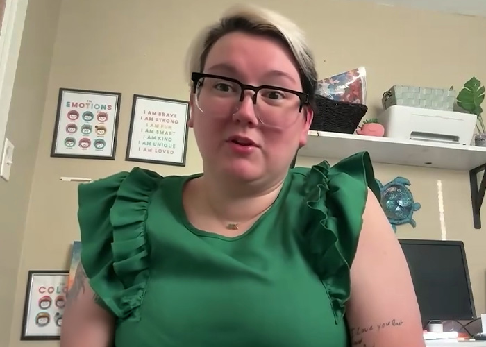 A woman wearing glasses and a green top speaking about a life-threatening illness after a Halloween activity.