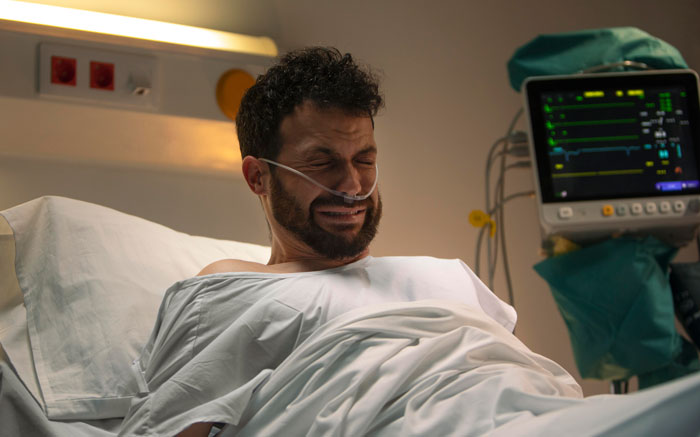 A man in a hospital bed crying before receiving heart surgery.