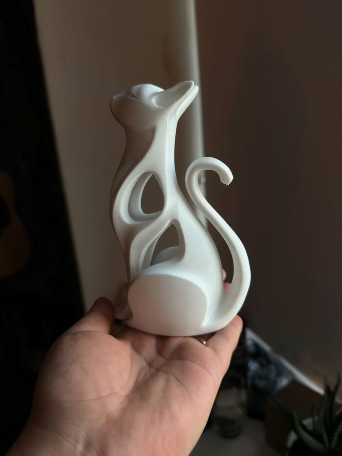 A white 3D printed cat statue with a sleek, minimalist design