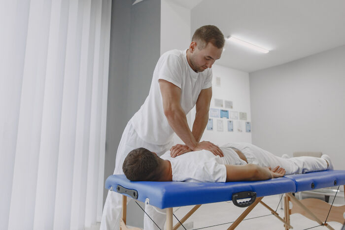 Male physical therapist or doctor treating a male patient on a medical massage table.
