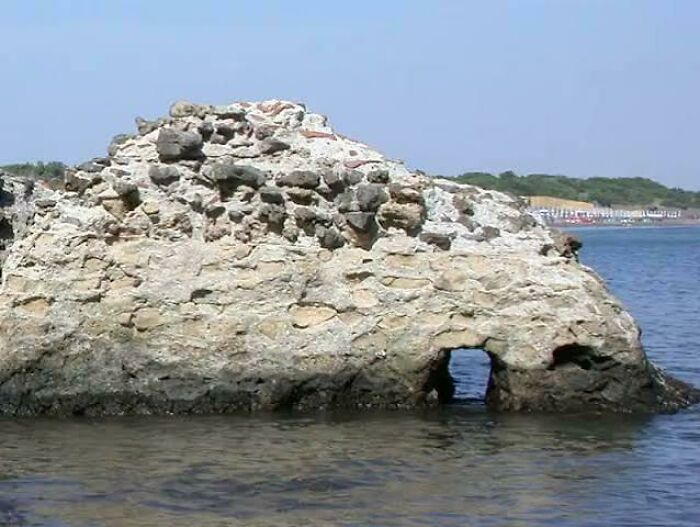 Ancient stone structure partially submerged in water with a small arch