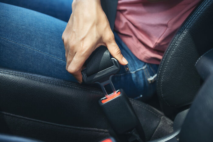 A driver fastening a seatbelt securely as part of essential emergency tips for car safety.