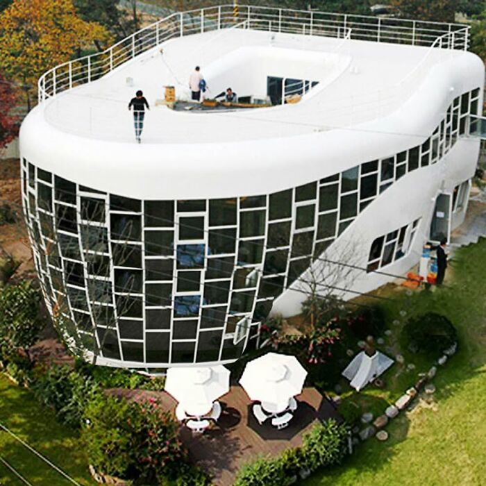 White futuristic building with irregular windows and rooftop terrace under construction