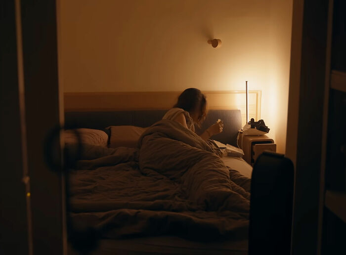 Woman lying in bed in a warmly lit room addressing female health issues Woman lying in bed in a warmly lit room addressing female health issues