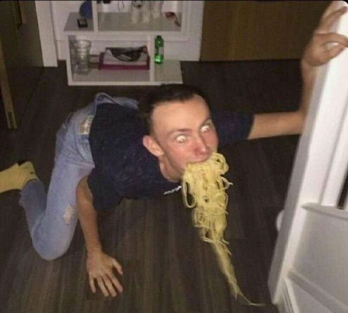 Cursed image of man on floor eating spaghetti from fridge