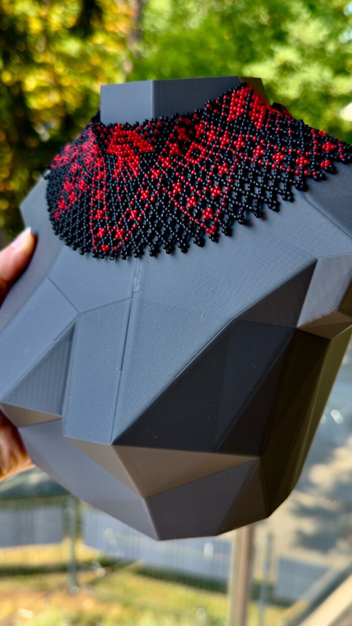 A black low-poly bust mannequin wearing a beaded necklace, showing clever 3D prints