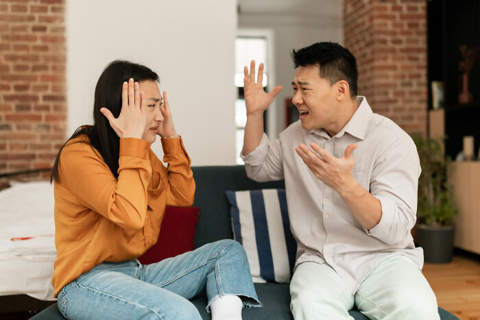 A couple arguing fiercely on a couch as part of divorce stories.