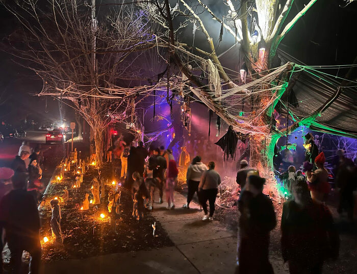 Crowd enjoying neighborhood epic Halloween display with spider webs and lights Crowd enjoying neighborhood epic Halloween display with spider webs and lights