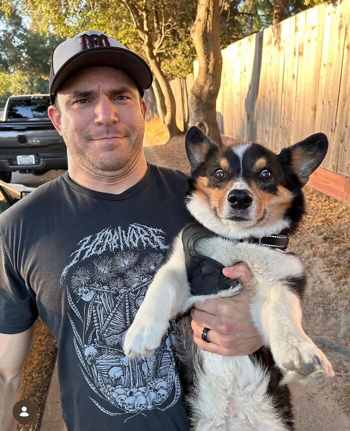 Man smiling next to his Corgi dog with a similar facial expression, showing pets who look like their owners.