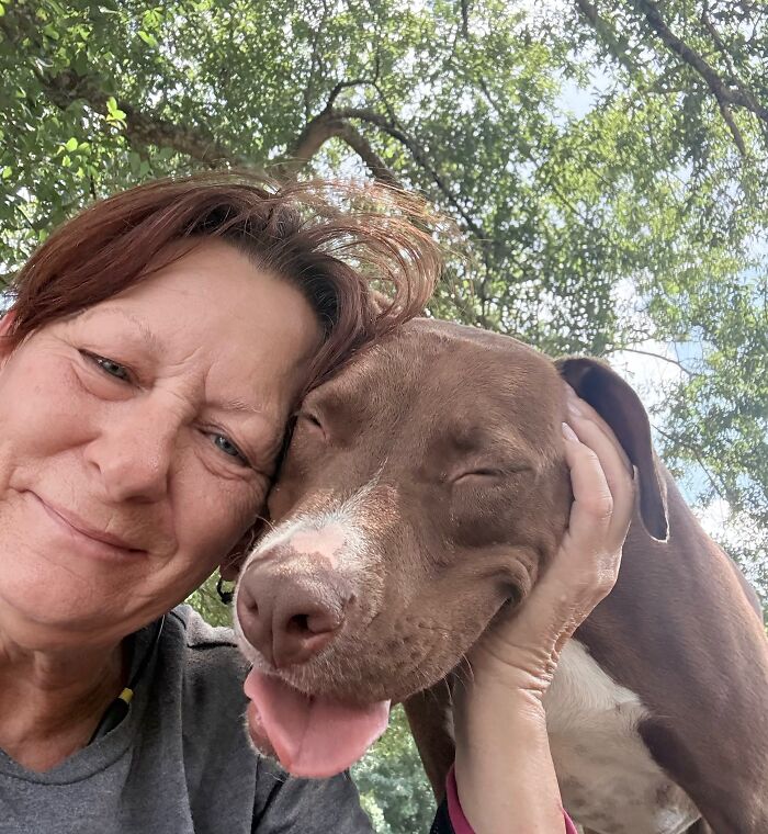 A happy woman smiling widely next to her squinting brown dog, showing pets look like their owners.