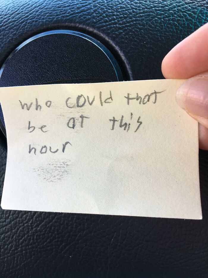 Found paper sticky note held in hand reading who could that be at this hour